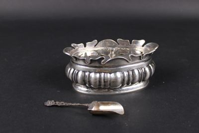 une bague en argent avec une cuillère posée sur une surface noire