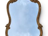 an ornately carved mirror with a blue sky in the background