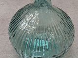 a green glass bottle sitting on the ground on the ground
