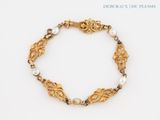 a close up of a gold bracelet with pearls on a white background
