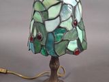 lampe avec un abat-jour en verre vert et rouge, montée sur un pied en métal