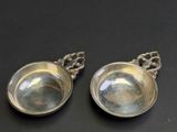 pair of silver plated spoons with chain handles on a black surface