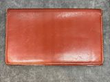 a brown leather wallet sitting on top of a gray carpet