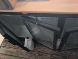a broken window on the floor next to a trash can