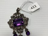 a close up of a necklace with a purple stone on it
