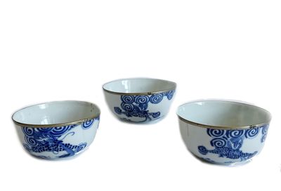 trois bols bleus et blancs ornés de motifs de dragons, posés sur un fond blanc