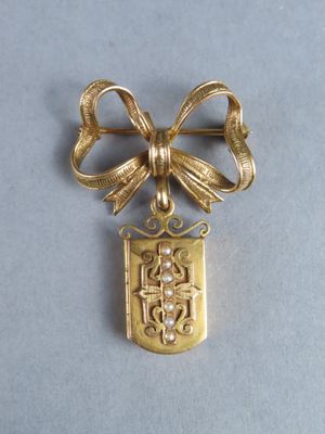 an image of a gold plated brooch with a bow on it