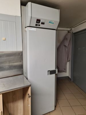 a white refrigerator in the corner of a room with tile flooring