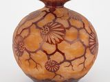 un vase marron orné de fleurs, posé sur un fond blanc