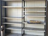 des étagères dans un garage, avec une poubelle et une autre poubelle à l'arrière-plan