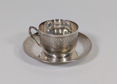 une tasse et une soucoupe en argent posées sur une soucoupe