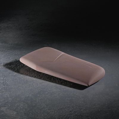 un objet rose posé sur une surface noire, sur fond noir