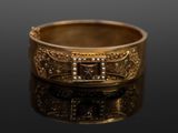 une image montrant un gros plan d'une bague en or posée sur une surface noire