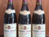 three bottles of wine sit on a table in front of a wooden wall