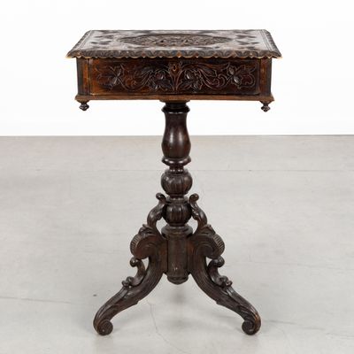 une vieille table en bois avec un plateau sculpté reposant sur un piédestal