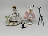 trois figurines représentant des femmes et une girafe posées sur une table