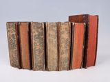 several old books stacked on top of each other on a white surface