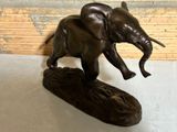 a statue of an elephant that is standing on a log