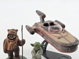 star wars figurines sit on a white surface next to a star wars vehicle