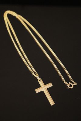 a gold cross necklace on a black background