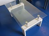 une table basse en verre posée sur un sol bleu dans une pièce