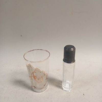 un petit verre et une petite bouteille posés sur une table