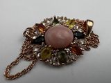 an image of a necklace with a pink stone surrounded by multicolored stones