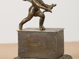 an antique bronze statue of a cupid holding a tennis racket