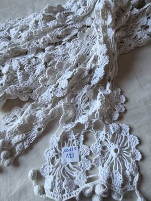 un gros plan d'une écharpe blanche au crochet posée sur une table