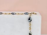 collier composé de perles noires et dorées montées sur un bloc de marbre blanc