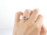 a woman ' s hand holding a ring with a purple stone on it