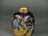 purple and gold vase with blue flowers on it on a gray surface