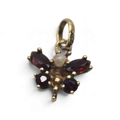 a close up of a gold plated flower charm with garnets