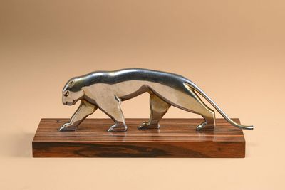 a metal sculpture of a cat on a wooden base