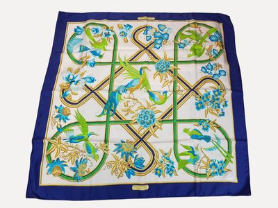 a close up of a blue and green scarf with birds and flowers
