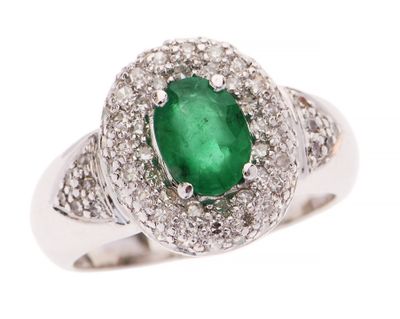 gros plan d'une bague avec une pierre verte entourée de diamants blancs
