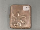 an antique silver cigarette case with a flower design on it