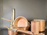 pots and pans sitting on a table with a spoon and spatula