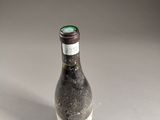 an empty bottle sitting on top of a table next to a white table