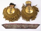 une paire de boucles d'oreilles plaquées or et un couteau posés sur un fond blanc