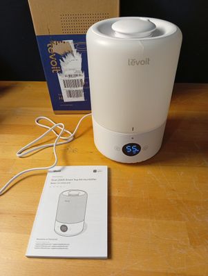 un humidificateur blanc posé sur une table en bois à côté d'une boîte