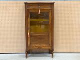 a wooden cabinet with a glass door and a clock on it