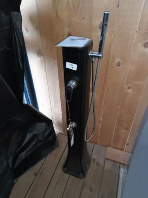 une douche posée sur un plancher en bois, à côté d'une chaise noire