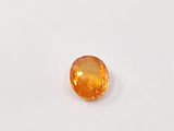 an orange sapphire stone on a white surface