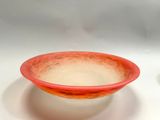 a red bowl sitting on a white plate next to a cup