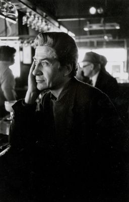 photographie en noir et blanc d'un homme assis à un bar, en train de parler au téléphone portable