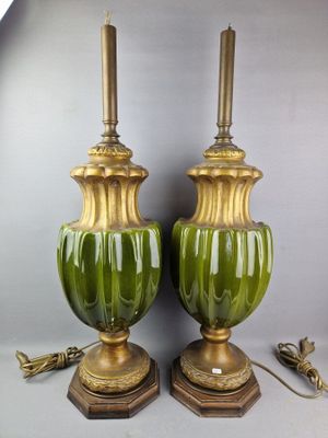 une paire de vases verts et dorés posés sur des socles en bois, sur fond gris
