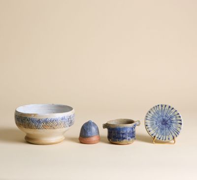 des bols et des tasses bleus et blancs posés sur une table, sur fond beige
