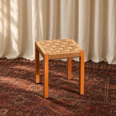 un gros plan sur un petit tabouret posé sur un tapis devant un rideau