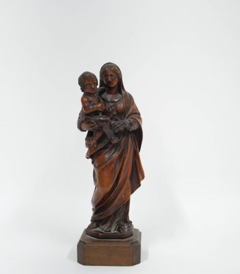 une statue représentant une femme tenant un enfant dans ses bras, posée sur un socle en bois